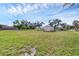 Large grassy backyard with a shed, mature trees, and a clear blue sky overhead at 612 Bayshore Rd, Nokomis, FL 34275