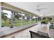 Enclosed patio with tile flooring, fan, table set, and views of the expansive landscaped yard at 612 Bayshore Rd, Nokomis, FL 34275