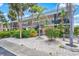 Two-story building with stairs, black railings, and tropical plants in a pebble landscape at 614 Guild Dr # 10, Venice, FL 34285