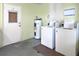 Community laundry room featuring two washing machines and hot water tank with door to exterior at 614 Guild Dr # 10, Venice, FL 34285