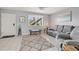 Cozy living room features tile flooring, comfortable gray furniture, and bright natural light from the window at 614 Guild Dr # 10, Venice, FL 34285