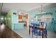 Open concept dining area connecting to a kitchen, featuring a wood table and cheerful turquoise walls at 614 N Waterway, Venice, FL 34285
