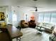 Bright living room with neutral tones, wood-look floors, ceiling fan, and ample natural light from large windows at 623 Leisure, Venice, FL 34285