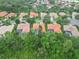 Wide aerial view of homes with orange tile roofs, verdant lawns, and dense trees at 6619 Pinefeather Ct, Bradenton, FL 34203