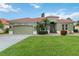 Charming green home featuring a well-manicured lawn, desert landscaping, and a red tile roof at 6619 Pinefeather Ct, Bradenton, FL 34203