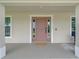 Covered front porch with a stylish pink front door, sidelights, and neutral exterior at 7257 Maguire Ln, Englewood, FL 34224