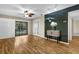 Open floor plan living room with wood floors, sliding doors to balcony, ceiling fan and track lights at 756 White Pine Tree Rd # 204, Venice, FL 34285