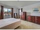 Bedroom with tan carpet, large windows with brown curtains, and two wooden dressers at 800 Capri Isles Blvd # 235, Venice, FL 34292