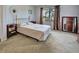 Bedroom with tan carpet, gold colored bed frame, brown curtains and view of trees at 800 Capri Isles Blvd # 235, Venice, FL 34292