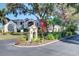 Community entrance sign amid lush landscaping and trees, with a view of the building and the American flag at 800 Capri Isles Blvd # 235, Venice, FL 34292