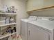 Laundry area with side-by-side washer and dryer, shelving for storage, and tiled floors at 800 Capri Isles Blvd # 235, Venice, FL 34292