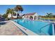 Community pool featuring a spacious deck, comfortable lounge chairs, and charming poolside pavilion with palm trees at 800 Capri Isles Blvd # 235, Venice, FL 34292