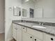 Bathroom with double sinks, granite countertop, white cabinets and framed mirrors at 9157 Genesee St, Port Charlotte, FL 33981