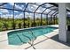 View of the pool with stairs and metal railing inside screened lanai at 9157 Genesee St, Port Charlotte, FL 33981