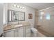 Bathroom with tiled shower, granite counters, white cabinetry and a framed mirror at 931 Inlet Cir, Venice, FL 34285