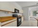 White kitchen with black oven and microwave, wooden countertops, and a sunlit breakfast nook at 9528 Knightsbridge Cir, Sarasota, FL 34238
