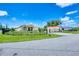 Charming yellow house with a gated entrance, lush lawn, and a clear blue sky at 102 Bayamo Dr, North Port, FL 34287
