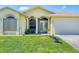 Inviting yellow home showcasing a well-manicured lawn and attached two-car garage at 102 Bayamo Dr, North Port, FL 34287