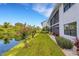 Exterior view of building with a pond behind the green lawn and landscaping at 1100 Capri Isles Blvd # 215, Venice, FL 34292