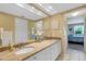 Bright bathroom featuring double sinks with granite countertops, large mirror, and access to the bedroom at 1100 Capri Isles Blvd # 215, Venice, FL 34292
