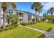Exterior view of charming condo buildings with lush landscaping, vibrant green grass, and inviting walkway at 1100 Capri Isles Blvd # 215, Venice, FL 34292