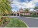 Elegant clubhouse exterior with lush landscaping, a circular driveway, and well-maintained grounds at 11192 Campazzo Dr, Venice, FL 34292