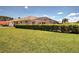 Backyard view of home featuring a screened pool enclosure with well-maintained lawn and privacy hedge at 1136 Deardon Dr, Venice, FL 34292