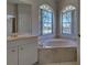 This bathroom features a soaking tub, corner windows, double sink vanity, and tile flooring at 1136 Deardon Dr, Venice, FL 34292
