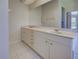 This bathroom features double sinks, vanity with white cabinets, a large mirror, and tile floors at 1136 Deardon Dr, Venice, FL 34292