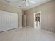 This bedroom includes tile flooring, a double door closet, a ceiling fan, and tan walls at 1136 Deardon Dr, Venice, FL 34292