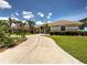 The front of this tan single-story home features a concrete driveway, green grass, and a blue sky with puffy white clouds at 1136 Deardon Dr, Venice, FL 34292