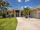 The front of this tan single-story home with a red tile roof features a walkway and a green lawn at 1136 Deardon Dr, Venice, FL 34292