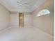 This main bedroom features light tile flooring, ceiling fan and an open doorway to the ensuite bathroom at 1136 Deardon Dr, Venice, FL 34292