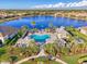 Aerial view of a community pool area with palm trees, cabanas, and a view of the surrounding lake and homes at 11739 Okaloosa Dr, Venice, FL 34293