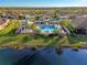 Aerial view of a community pool with palm trees, cabanas, and a scenic lake backdrop at 11739 Okaloosa Dr, Venice, FL 34293