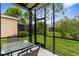 Screened lanai features a glass top table and seating, creating an inviting outdoor living space with lush green views at 11819 Tempest Harbor Loop, Venice, FL 34292