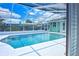 Inviting private screened-in pool surrounded by a white deck, lush landscaping, and a clear blue sky at 1198 Jamaica Rd, Venice, FL 34293