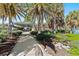 Palm-lined walkway leads to a covered beach pavilion, with lush landscaping and mature trees at 1211 Capri Isles Blvd # 6, Venice, FL 34292