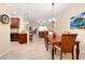 Open floor plan with dining table, kitchen bar seating, and view to the living room and sliders to lanai at 12187 Amica Loop, Venice, FL 34293
