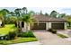 Villa featuring a beautiful tile roof, lush landscaping, and a brick paver driveway at 12187 Amica Loop, Venice, FL 34293