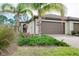 Charming home exterior with a well-maintained lawn, lush landscaping, and a two-car garage at 12187 Amica Loop, Venice, FL 34293