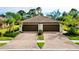Villa featuring a beautiful tile roof, lush landscaping, and a brick paver driveway at 12187 Amica Loop, Venice, FL 34293