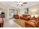 Living room featuring comfortable leather furniture, ceiling fan, and sliding glass doors to the outside at 12187 Amica Loop, Venice, FL 34293