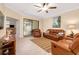 Spacious living room with comfortable leather furniture, ceiling fan, and sliding glass doors to lanai at 12187 Amica Loop, Venice, FL 34293