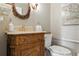 Cozy bathroom featuring an ornate wood vanity, round mirror, and neutral tones at 1234 Harbor Town Way, Venice, FL 34292
