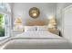 This bright bedroom has ample natural light, white walls, and a light grey upholstered headboard at 1234 Harbor Town Way, Venice, FL 34292