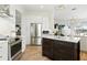 Bright kitchen features white cabinetry, stainless steel appliances, gold hardware, island, and hardwood floors at 1234 Harbor Town Way, Venice, FL 34292