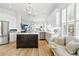 Open kitchen with large island, stainless steel appliances, white cabinets, hardwood floors, and seating area at 1234 Harbor Town Way, Venice, FL 34292