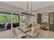 Dining area with a modern chandelier, wood table, and views of the screened-in patio and pool at 12404 Destin Loop, Venice, FL 34293