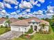Beautiful home with a tile roof, three-car garage, and a lush lawn with manicured landscaping and brick paver driveway at 12404 Destin Loop, Venice, FL 34293